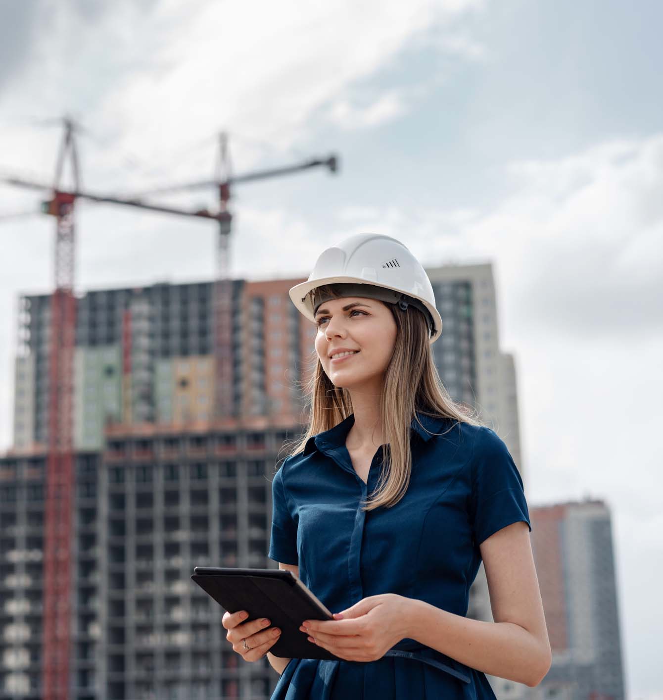 Female construction engineer. Architect with a tablet computer at a construction site. Young Woman looking, building. Young Woman look in camera, building site place background.